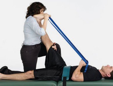 A woman is doing an Active Isolated Stretching with a blue strap.