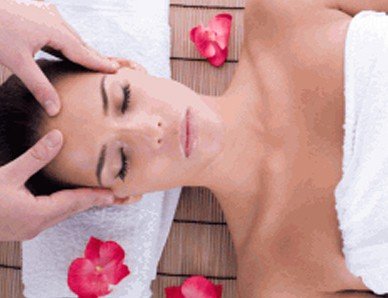 A woman indulging in a soothing massage experience enhanced with delicate rose petals on her head, offered through exclusive classes and workshops.
