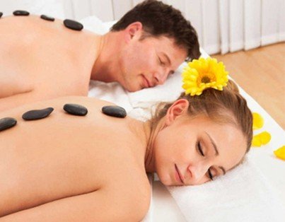 Two people experiencing Natural Calm while laying down on a bed with stones on their backs.