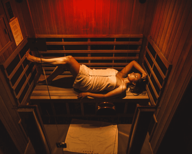 A woman laying down in an infrared sauna.